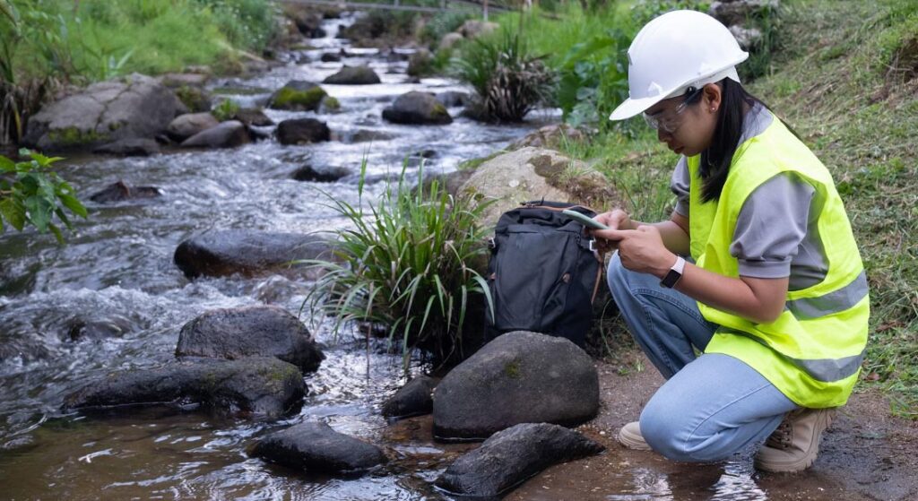 Environmental field technician collecting water quality data along a rocky stream, demonstrating Halker’s environmental services expertise in watershed monitoring, regulatory compliance, and ecological impact assessment.