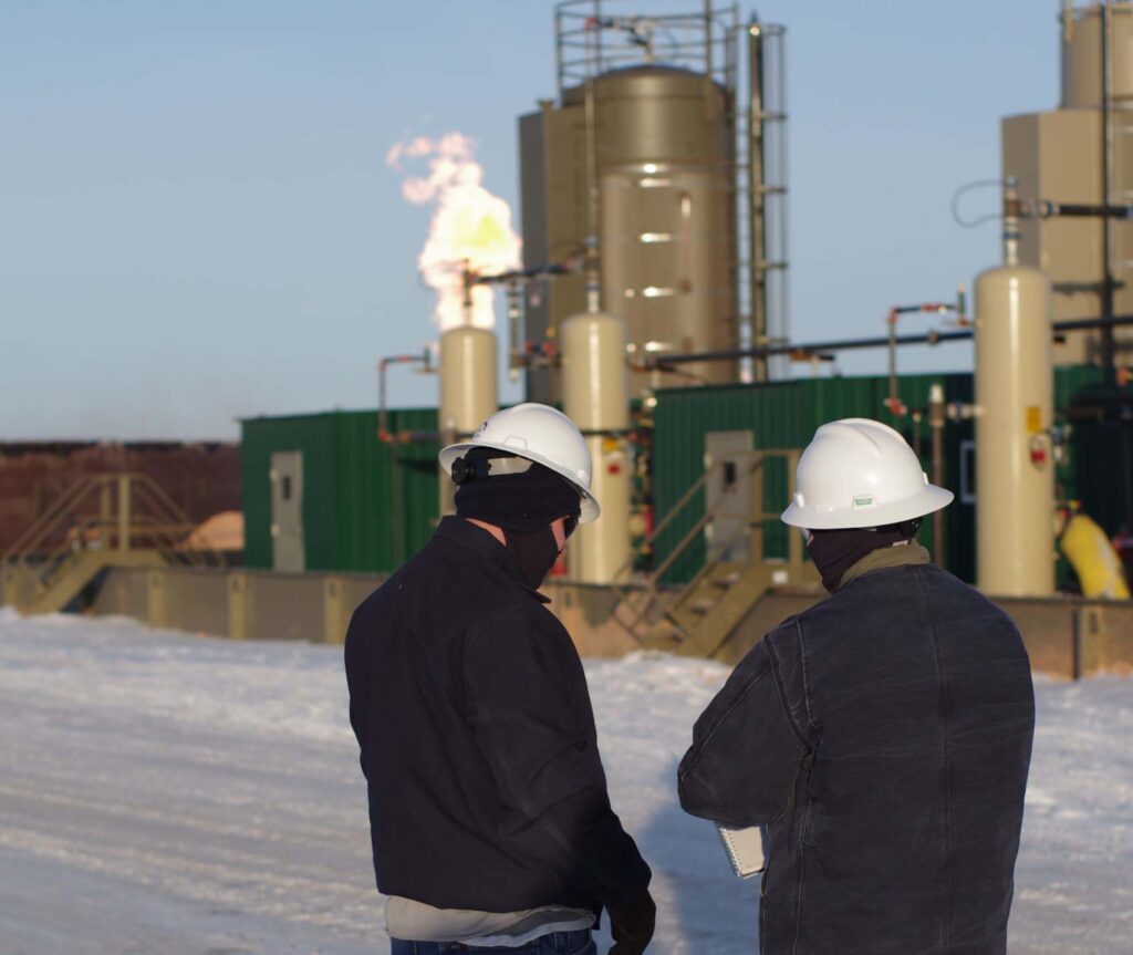 Engineers in hard hats observing an active flare stack at a midstream facility, emphasizing Halker’s expertise in flare system analysis, emissions management, and safety-focused flare study evaluations for oil and gas operations.