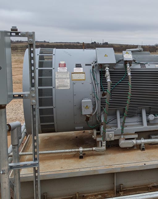 Large industrial electric motor with connected conduit and grounding cables at an energy facility, highlighting Halker’s expertise in electrical engineering, equipment reliability, and power systems support.