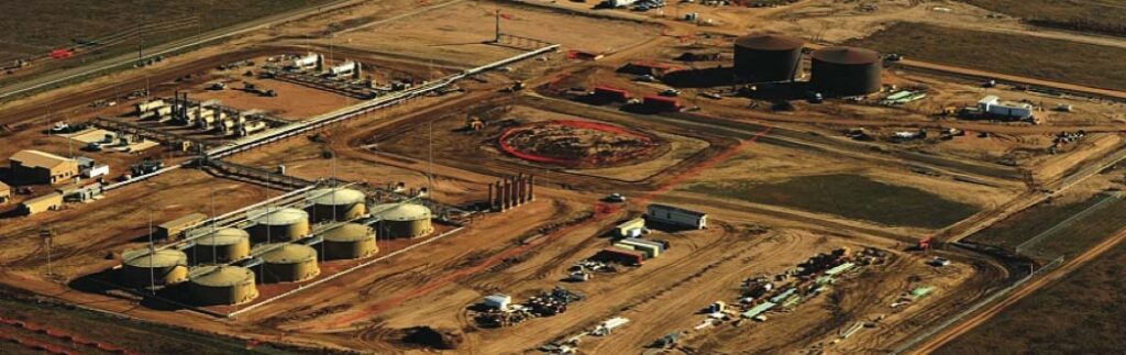 Aerial view of central processing facilities featuring storage tanks, process vessels, construction activity, and interconnected pipeline infrastructure, emphasizing Halker’s expertise in designing and engineering large-scale oil and gas processing centers that support efficient field operations and production throughput.