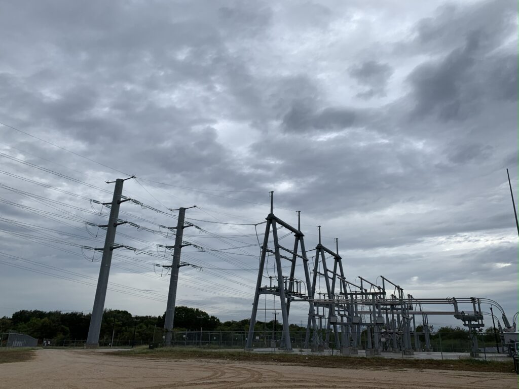 High-voltage transmission structures and substation equipment under overcast skies, illustrating Halker’s expertise in supporting city-operated distributed energy resource (DER) adoption and modern electric infrastructure planning.
