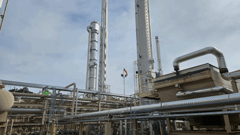 Natural gas processing facility with tall distillation towers, interconnected process piping, and equipment platforms, illustrating Halker’s expertise in gas plant optimization, throughput improvement, and operational efficiency engineering.
