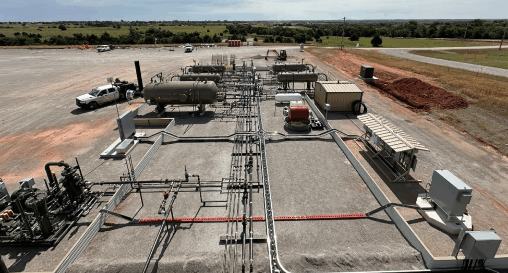 A Permian Basin oil and gas production site with interconnected piping, storage vessels, and equipment laid out across a gravel pad, illustrating Halker’s expertise in OOOOb regulatory compliance walkdowns, emissions assessment, and facility readiness verification.