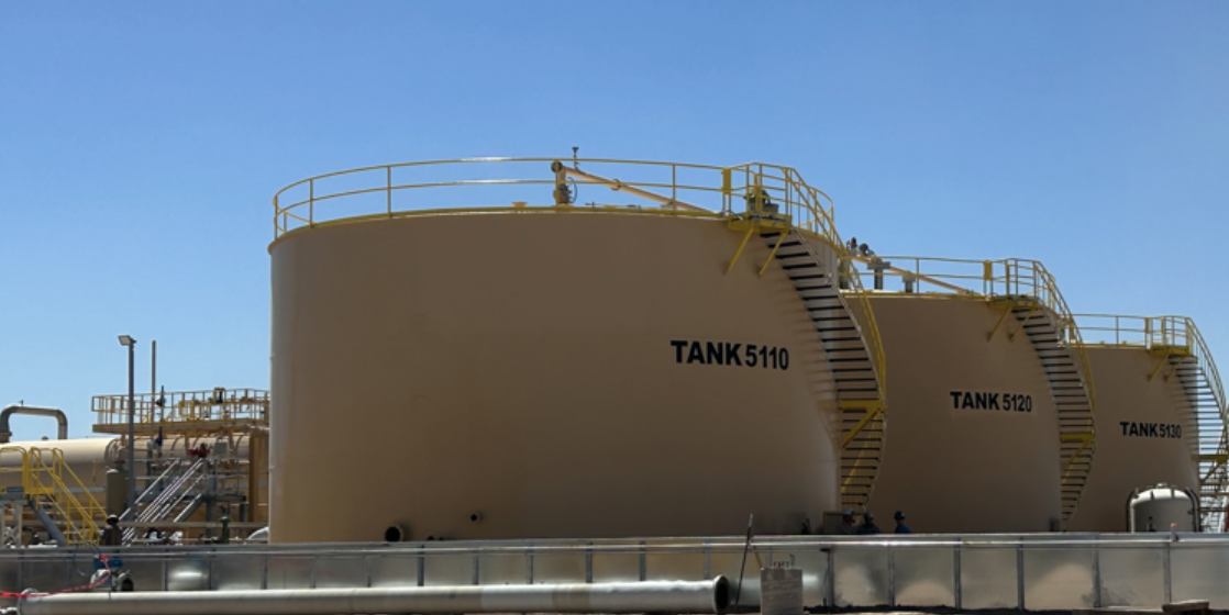 Large above-ground SWD storage tanks labeled TANK 5110 and TANK 5120 with access stairways and safety railings, showcasing Halker’s expertise in Salt Water Disposal commissioning, construction support, and facility startup operations.