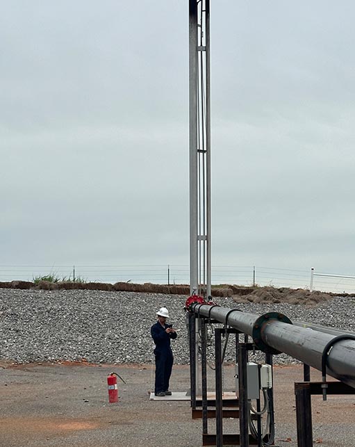 Halker Engineer inspecting an above-ground pipeline and flare stack ignition system at an oil and gas facility, demonstrating Halker's expertise in mechanical engineering, pipeline integrity, and safe equipment operation.