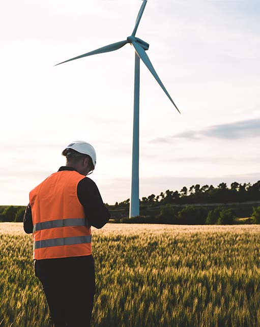 Engineer conducting field evaluation at a utility-scale wind turbine installation, capturing Halker's expertise in renewable energy development, performance assessment, and integrated wind power engineering solutions