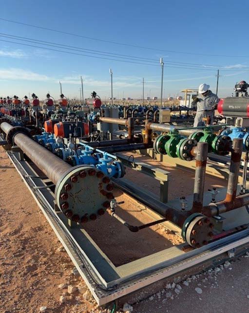 Halker Process Engineer in the field reviewing Oilfield production header system with large-diameter piping, valves, and manifold equipment during field operations, demonstrating Halker’s expertise in process engineering, facility design, and reliable upstream oil and gas infrastructure.