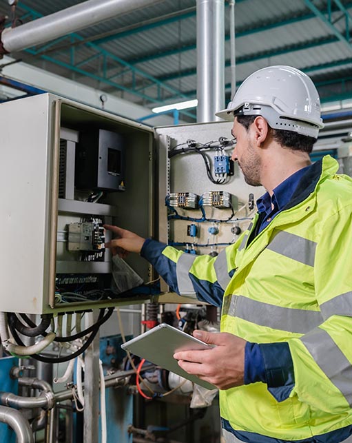Engineer inspecting an industrial control panel with instrumentation wiring and system components, representing Halker’s expertise in automation, SCADA integration, and reliable facility operations support.
